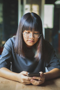 Girl using mobile phone sitting at cafe