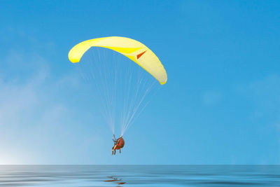 Man paragliding over sea against clear blue sky