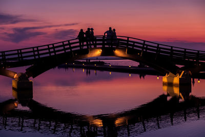 Silhouette people on bridge against sky during sunset