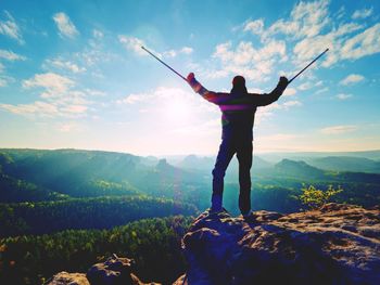 Rear view of man standing on mountain against sky