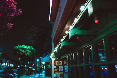 Illuminated street light by buildings in city at night