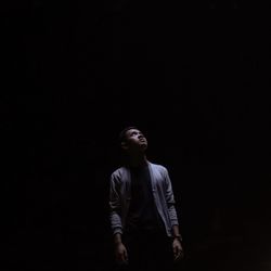 Full length of man looking away against black background