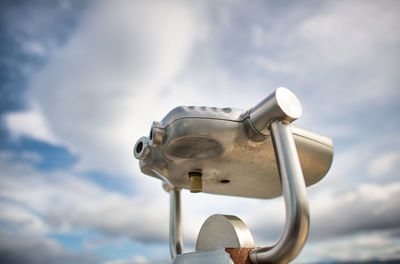 Low angle view of coin-operated binoculars against sky