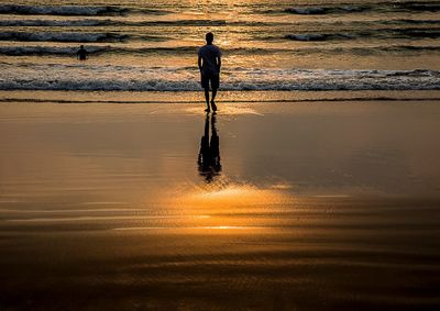 Silhouette man standing at beach during sunset