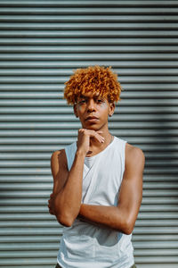 Portrait of young woman standing against wall