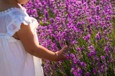 Midsection of woman standing amidst flowers