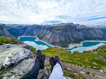 Low section of man standing on mountain against sky