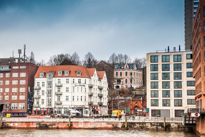 Residential buildings by river against sky in city