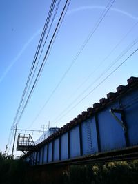 Low angle view of electricity pylon against blue sky