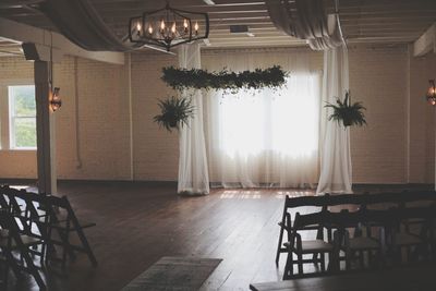Empty chairs and table against window in building
