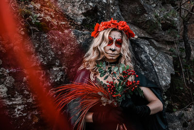 Closeup portrait of calavera catrina. young woman with sugar skull makeup and red flowers. dia 