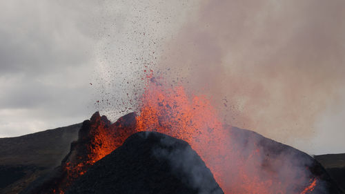 Scenic view of volcanic mountain against cloudy sky