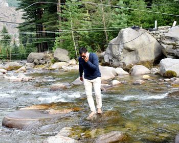 Man standing on rock against waterfall