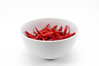 Close-up of red chili peppers in bowl against white background