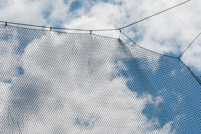 Low angle view of chainlink fence against sky