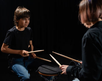 Musicians playing drum against black background