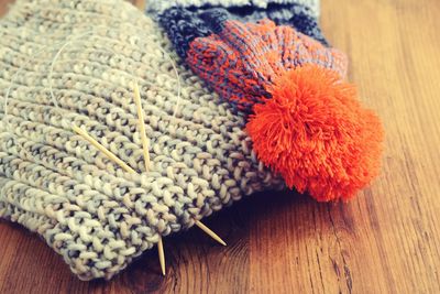 Close-up of knitting needles with hat and scarf on wooden table