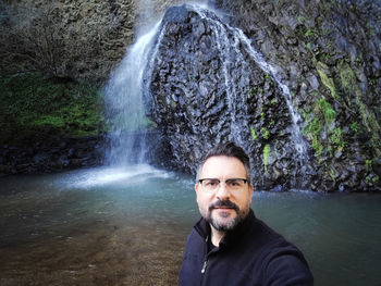 Portrait of man against waterfall