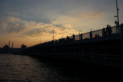 Silhouette of bridge over river during sunset