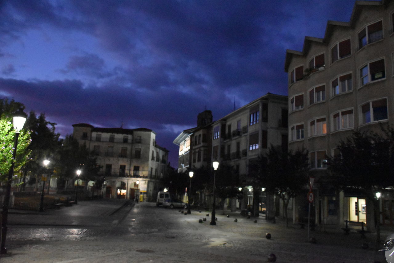 ILLUMINATED STREET AMIDST BUILDINGS AT NIGHT