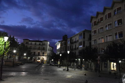 Street amidst buildings against sky at dusk