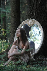 Portrait of young woman sitting in forest