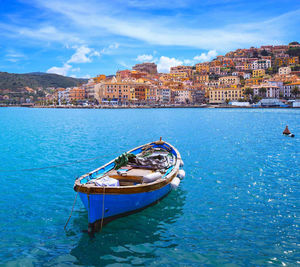 Boat moored in sea with townscape in background