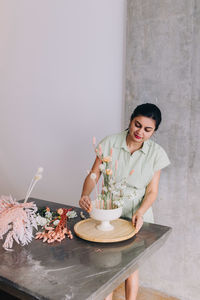 Woman of indian ethnicity of 30-34 years creating a centerpiece in ikebana style floral design