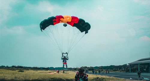 People paragliding on field against sky