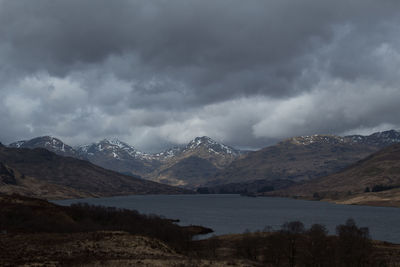 Scenic view of lake by mountains against sky