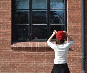 Rear view of woman standing against window of building