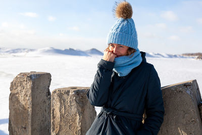 Beautiful modern urban young woman wearing blue knitting hat basks in cold weather 