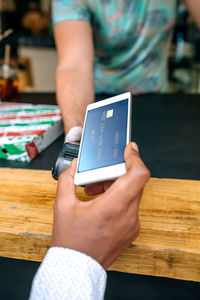 Cropped hand of man paying through mobile