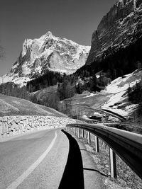 Road by snowcapped mountains against sky