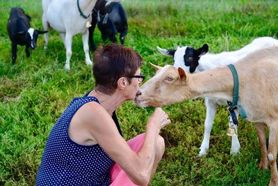 Woman kissing goat on field