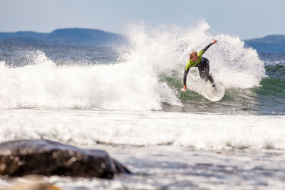 Man surfing in water against sky