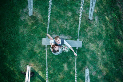 Portrait of bride and groom on swing at park