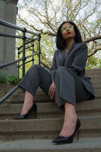 Portrait of young woman sitting on steps at park