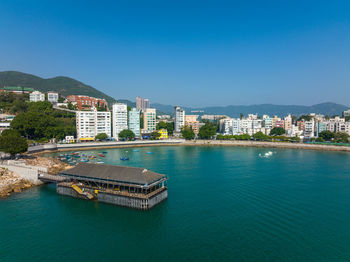 Buildings by sea against clear blue sky