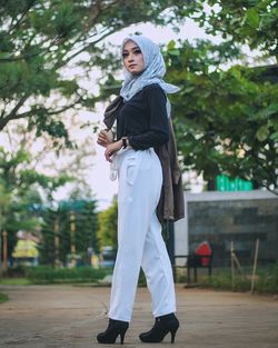 Full length of young woman standing on footpath