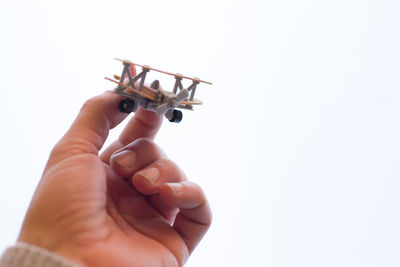 Close-up of hand holding small toy over white background