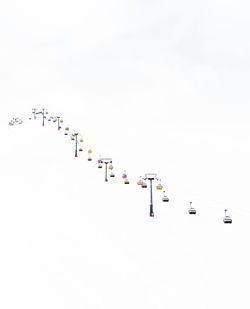 Ski lifts on snowcapped mountains against clear sky