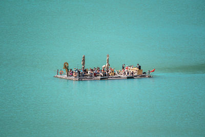 People on boat in sea against blue sky