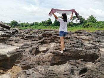 Rear view of woman standing on land against sky