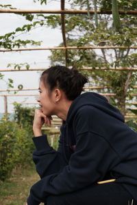 Young woman sitting by tree