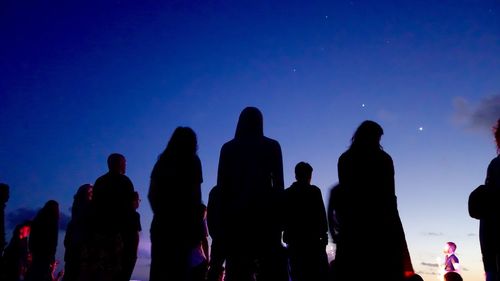 Silhouette people against sky at night