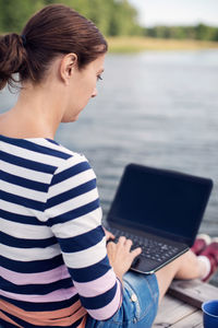 Full length side view of mature woman using laptop on pier