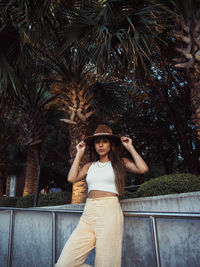 Portrait of young woman standing against trees