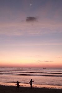 Silhouette people on beach against sky during sunset