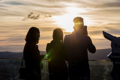 Silhouette people standing against sky during sunset